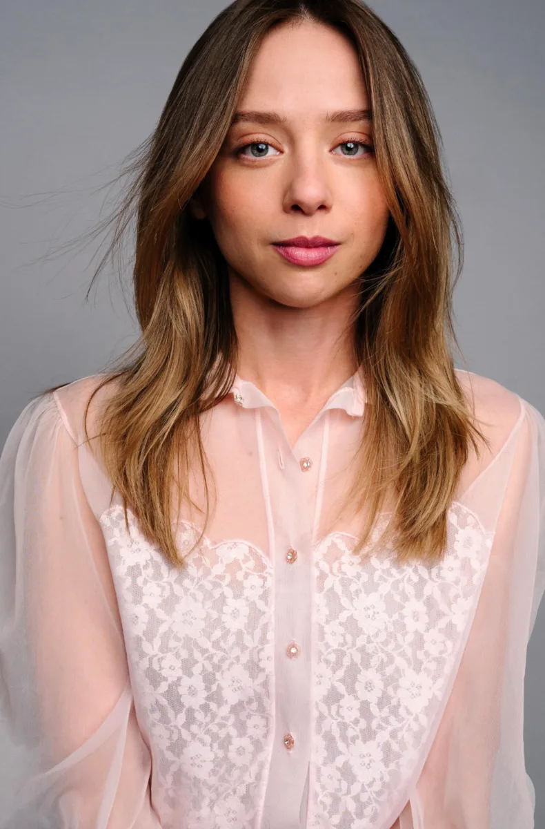 Anna Lore headshot with long hair and a sheer blouse