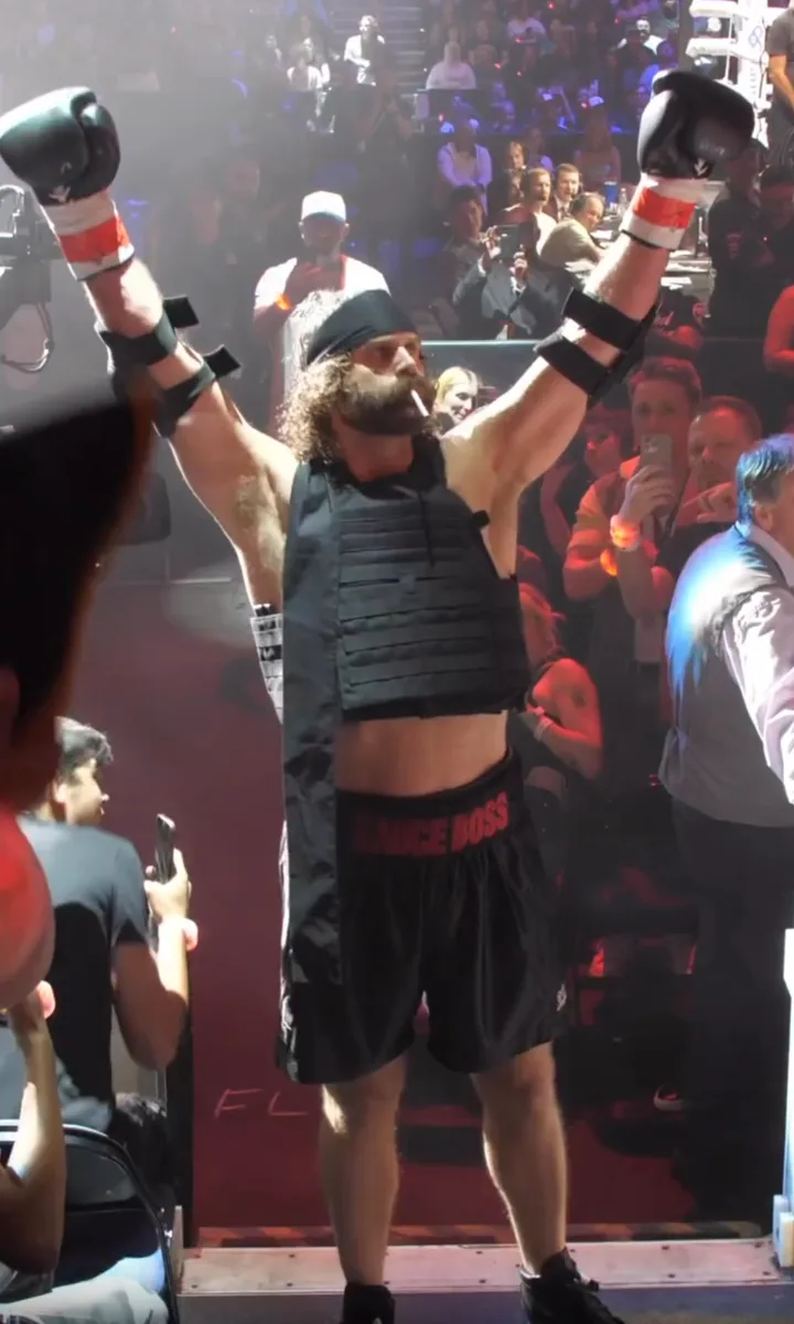 Harley Morenstein entering a boxing ring with gloves raised in front of a crowd