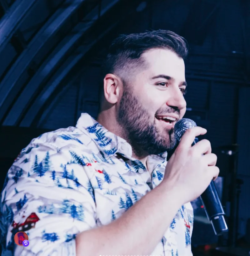 Matt Raub singing into a microphone in a floral shirt