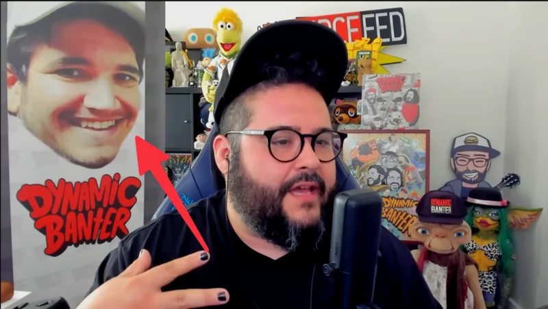 A red arrow pointing at a Dynamic Banter poster of Ryan Farroki’s smiling face while Steve Zaragoza talks, unbothered
